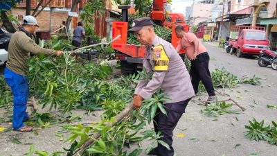 Bhabinkamtibmas Bantu Dinas LH Lakukan Pembersihan Dahan Pohon di Pinggir Jalan 
